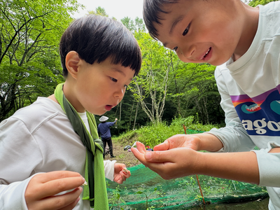 Two children share quiet excitement over something small and alive.