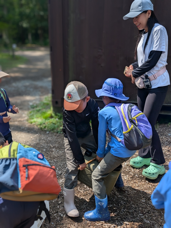 Children work together to lift a heavy container, adjusting their grip as a team.