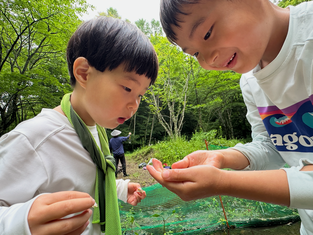 Two children share quiet excitement over something small and alive.